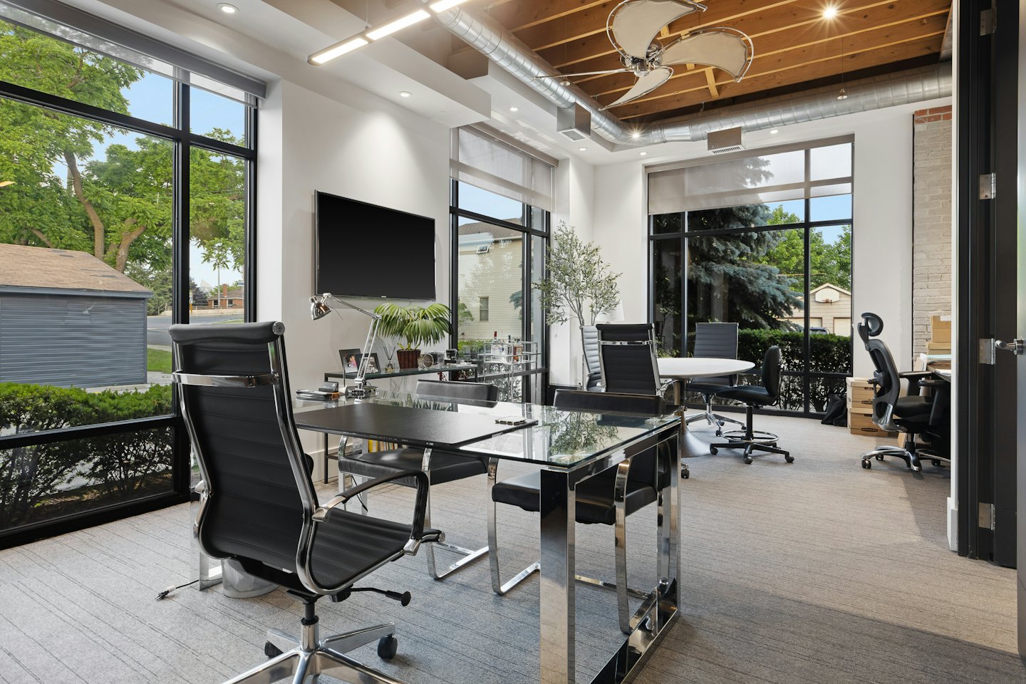 Oficina moderna con escritorios de cristal y sillas ergonómicas.