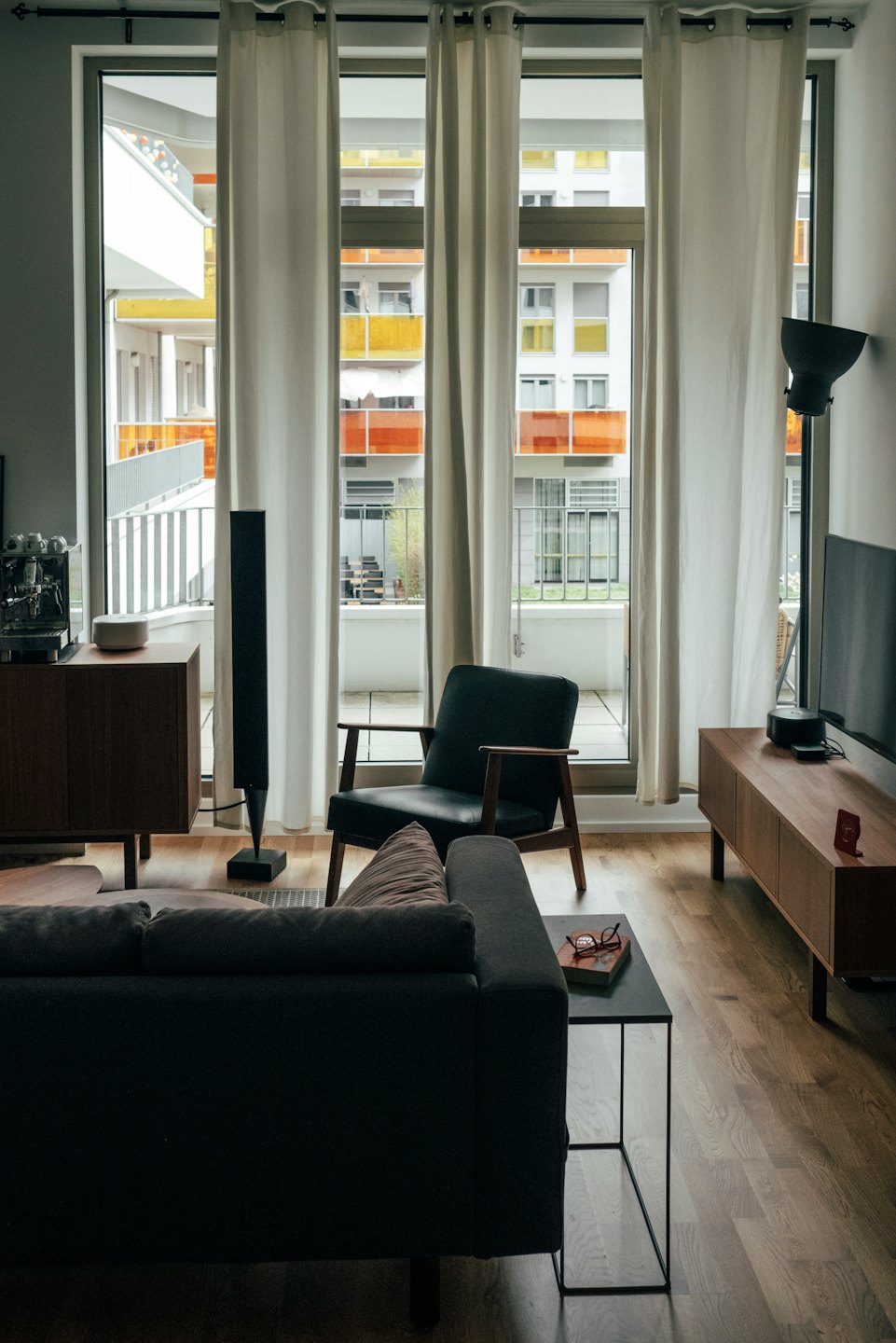 Sala de estar moderna con sofá gris y sillón negro cerca de las ventanas.